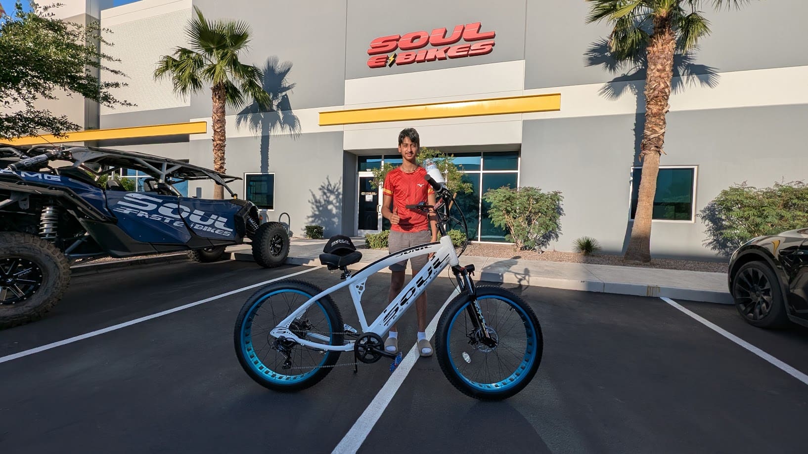 Person standing with a bicycle outside shop.