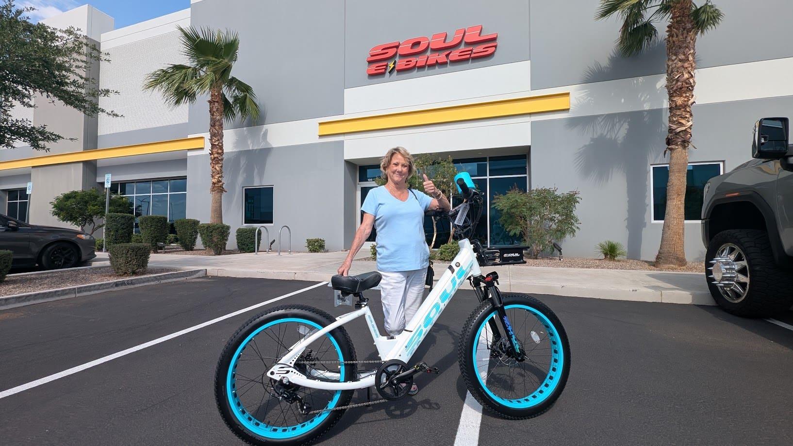 Woman standing with bicycle outside a store.