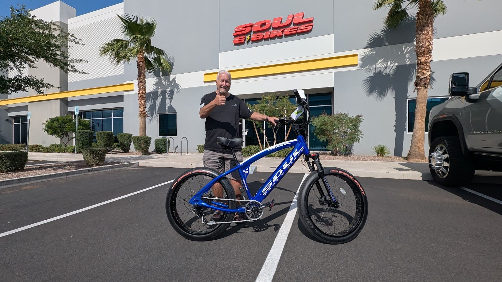 Man with blue bicycle outside a store.