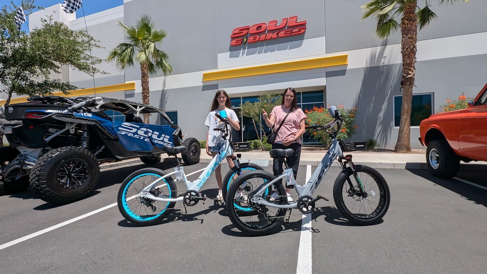 Two people with electric bikes outside store.