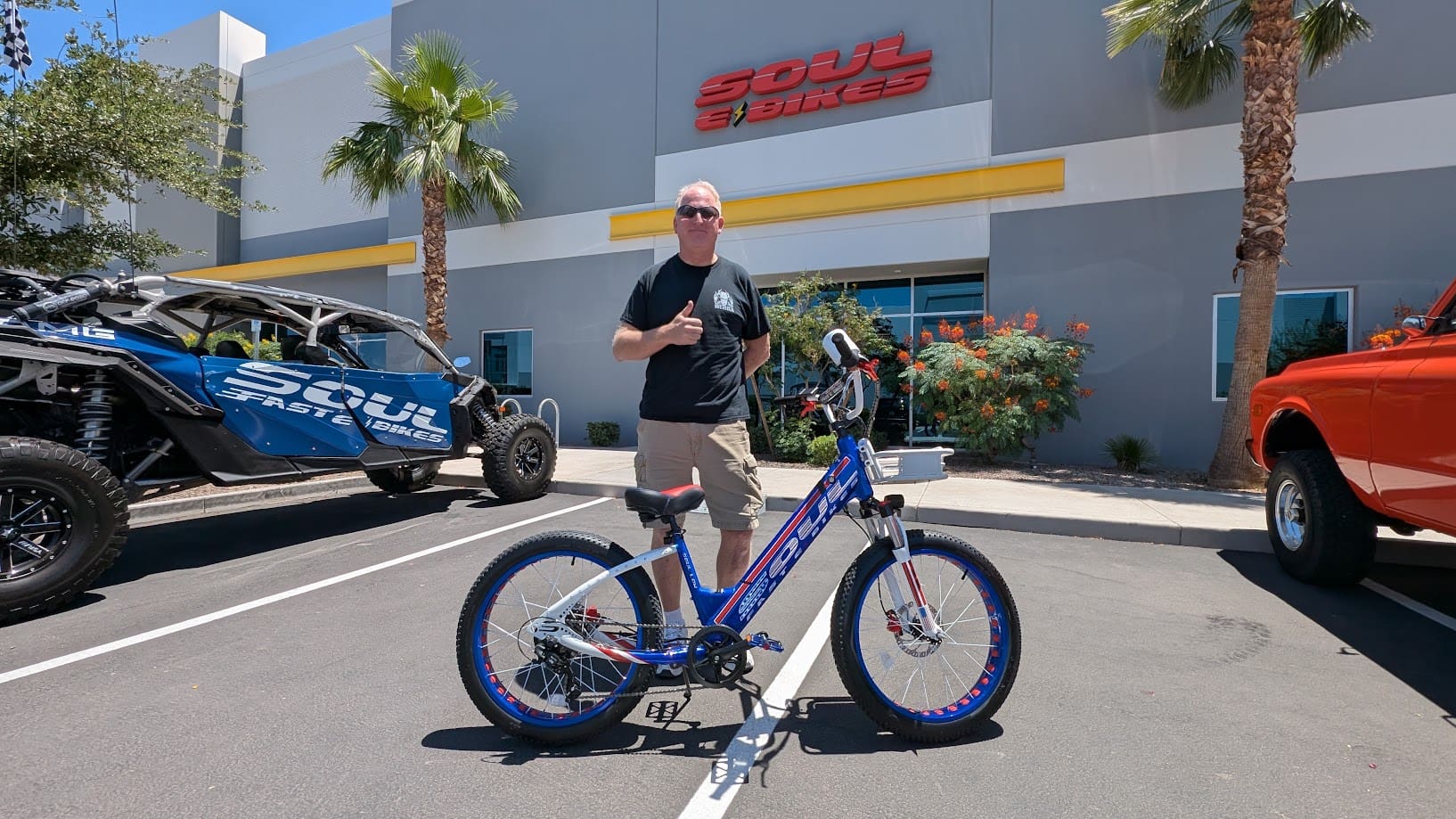 Man posing with blue bike outside store.