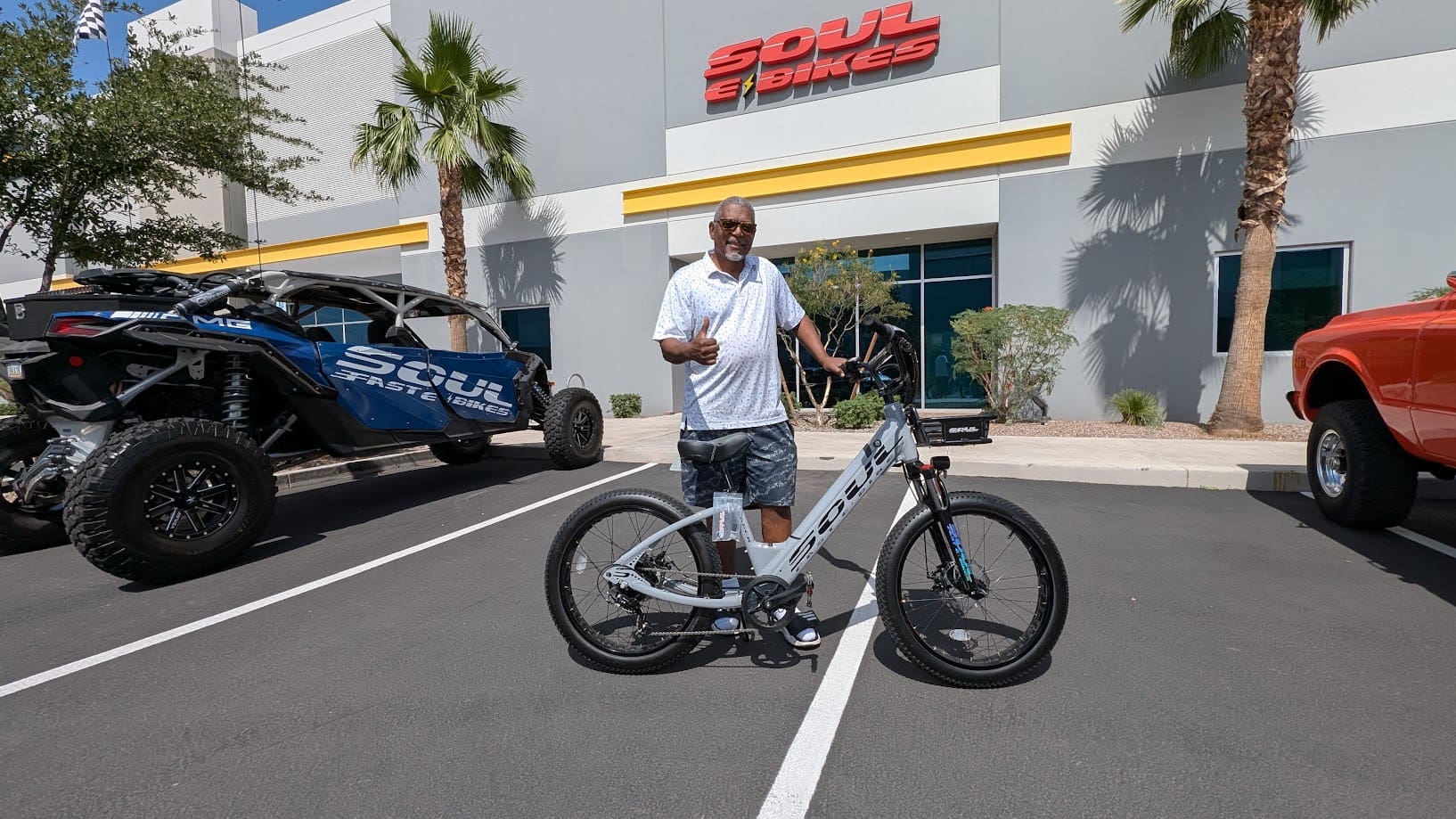 Man standing with bicycle outside shop.