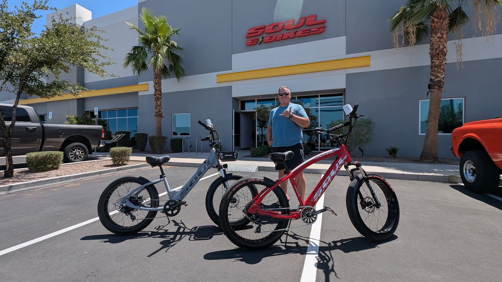 Man standing with two bicycles outside store.