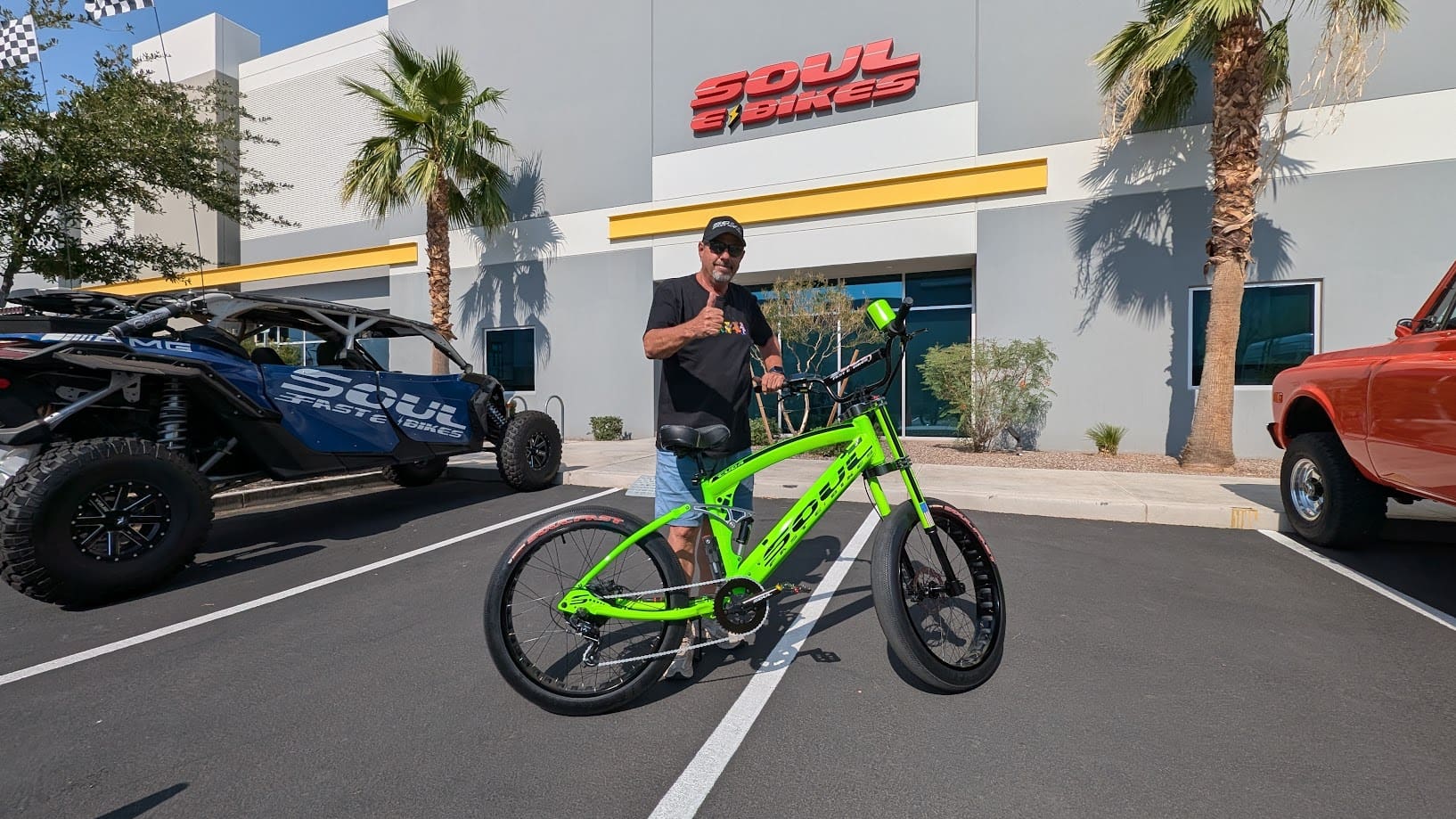 Man posing with green electric bike outside.