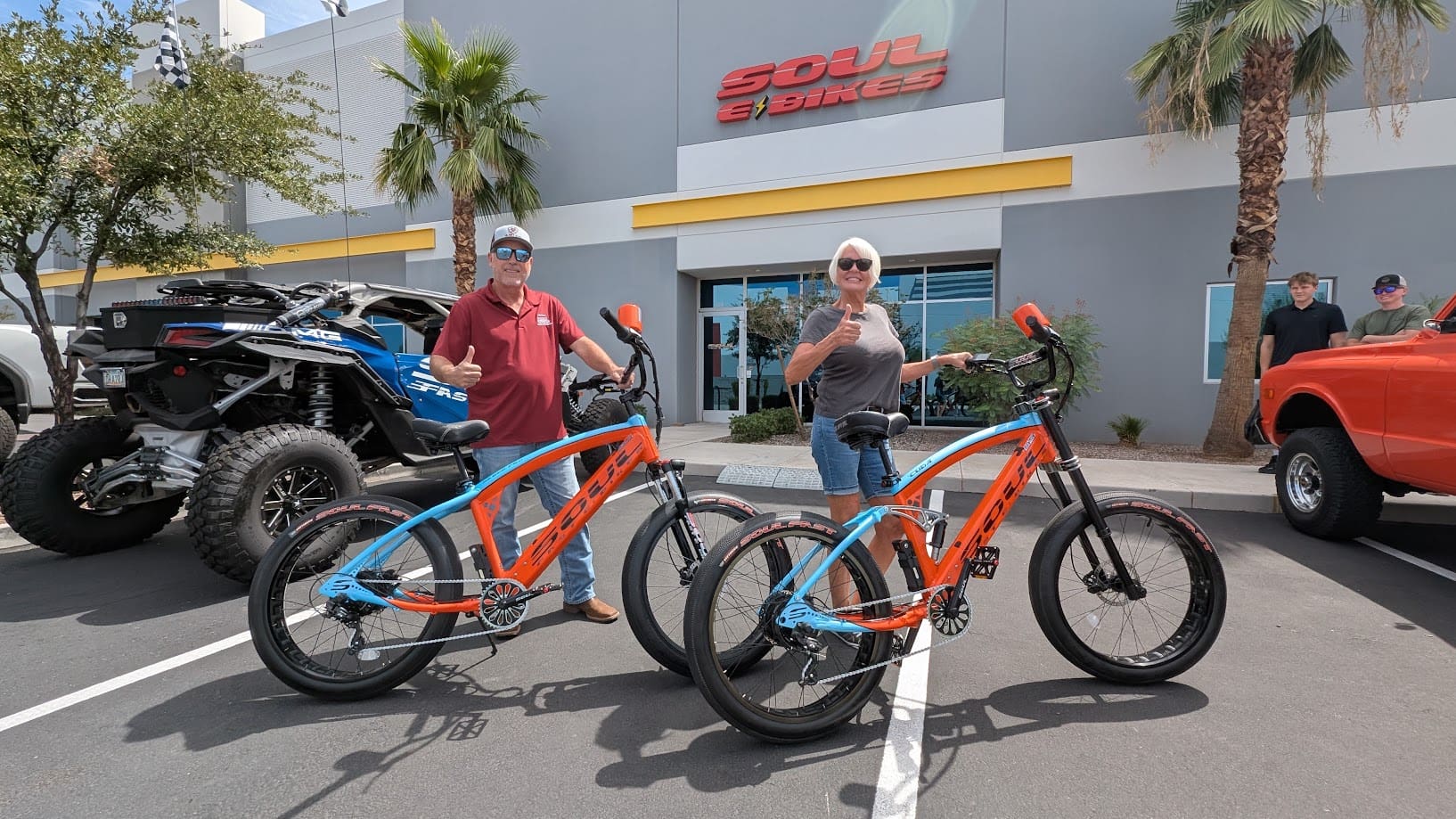 Two people with electric bicycles outside store.