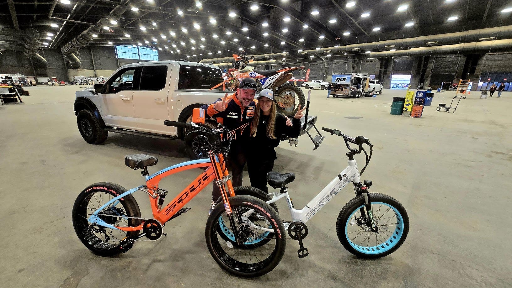 Two people with electric bikes indoors.