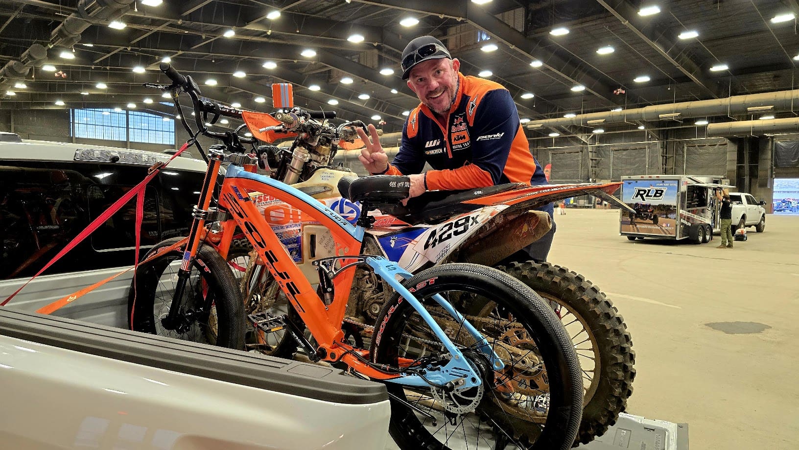 Man with dirt bike in large indoor space.