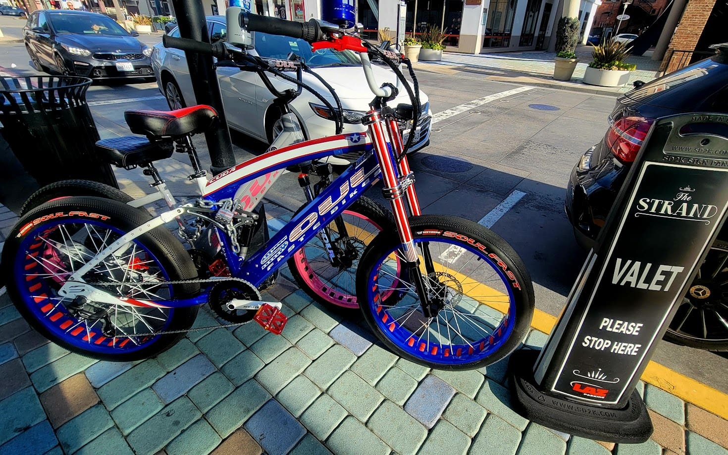 Bicycles parked near valet sign on street.