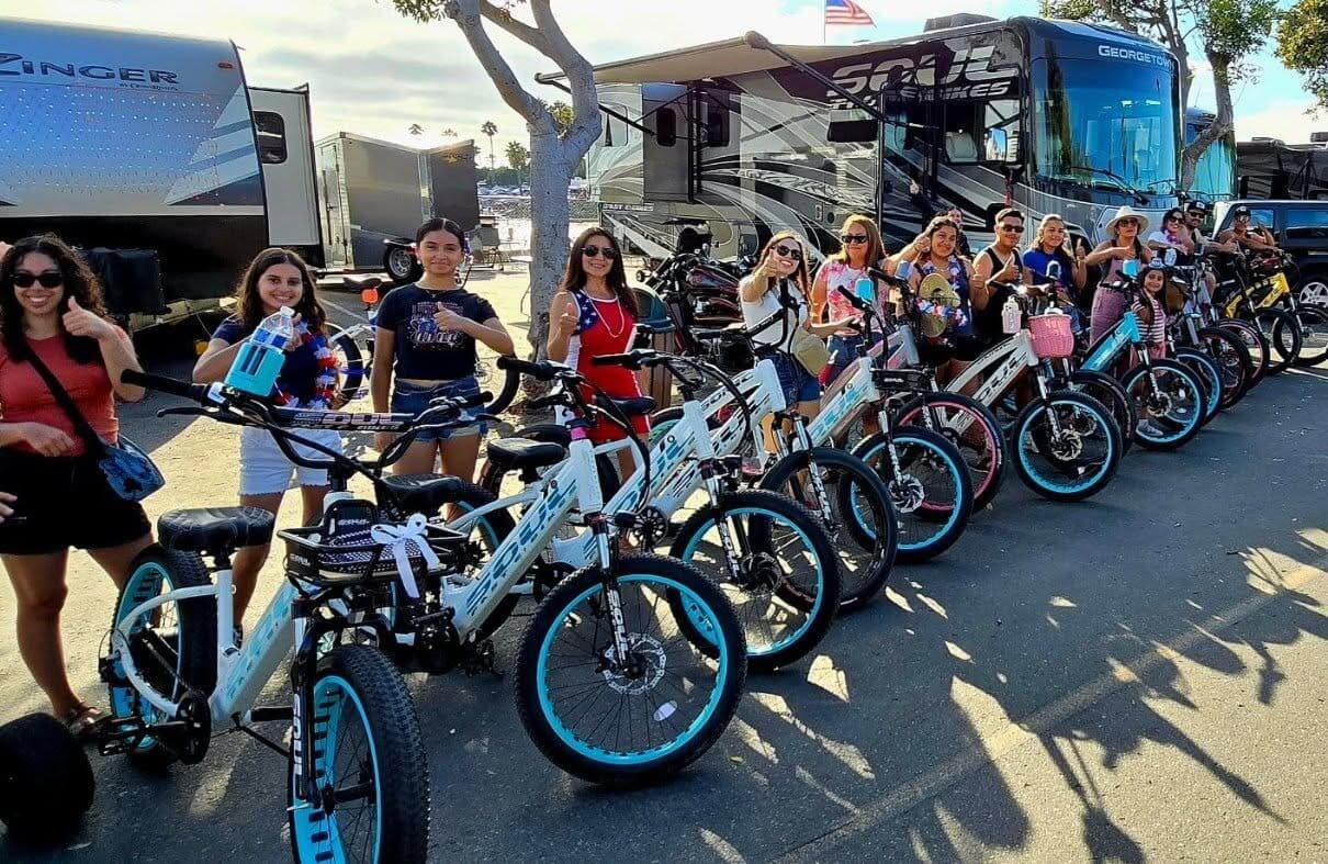 Group of women with bicycles near RVs.