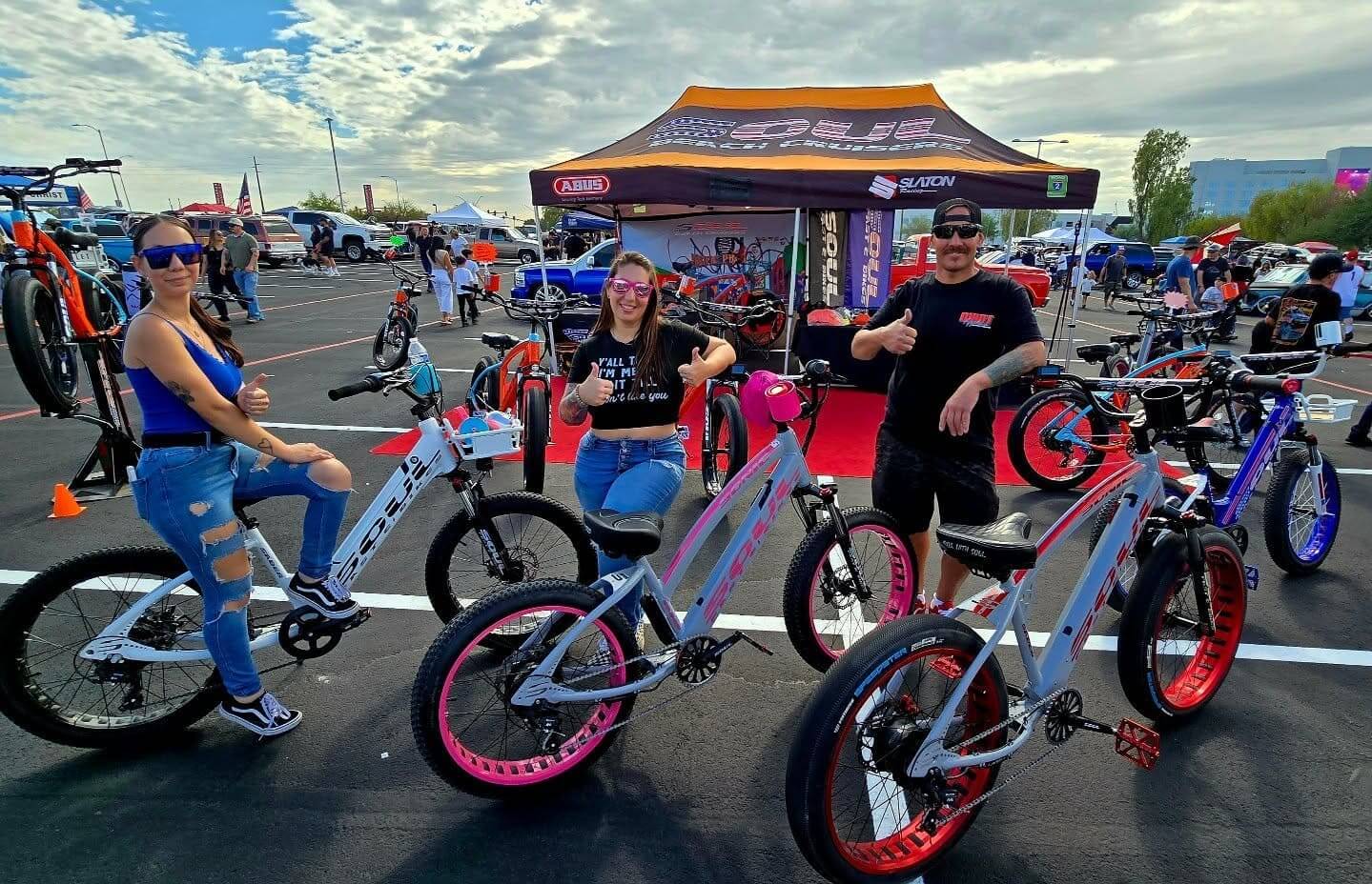 People posing with electric bikes at event.
