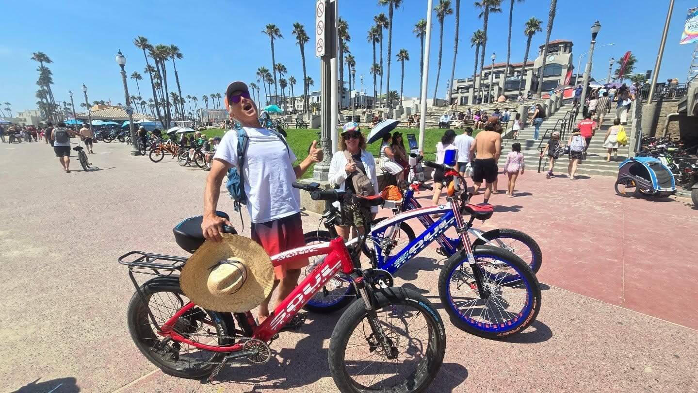 People with bikes on sunny boardwalk.