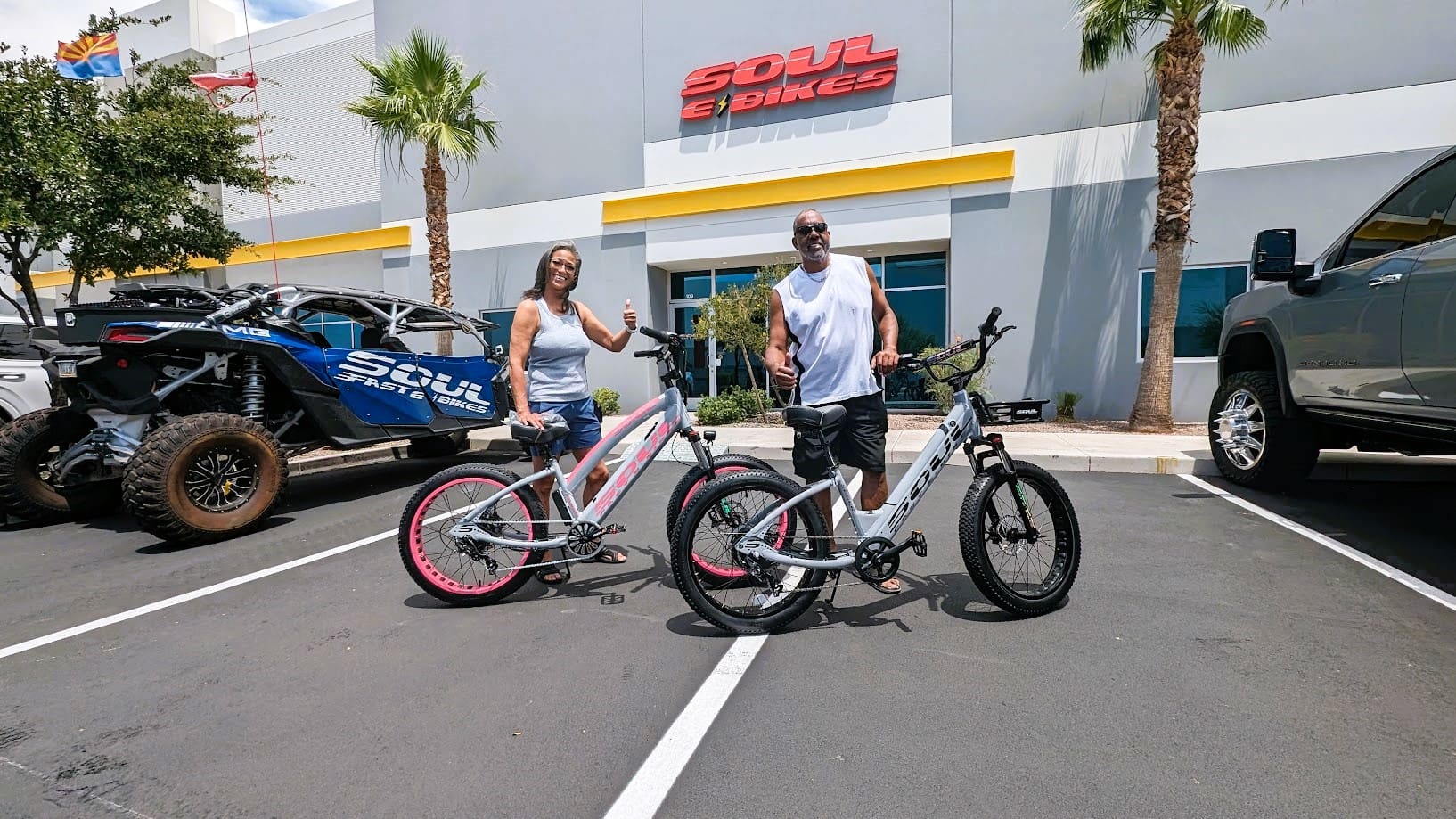 Two people with bicycles in parking lot.