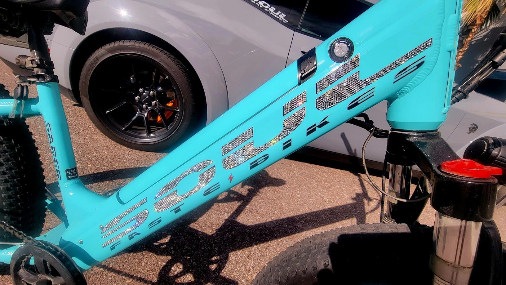 Turquoise bike frame near a parked car.