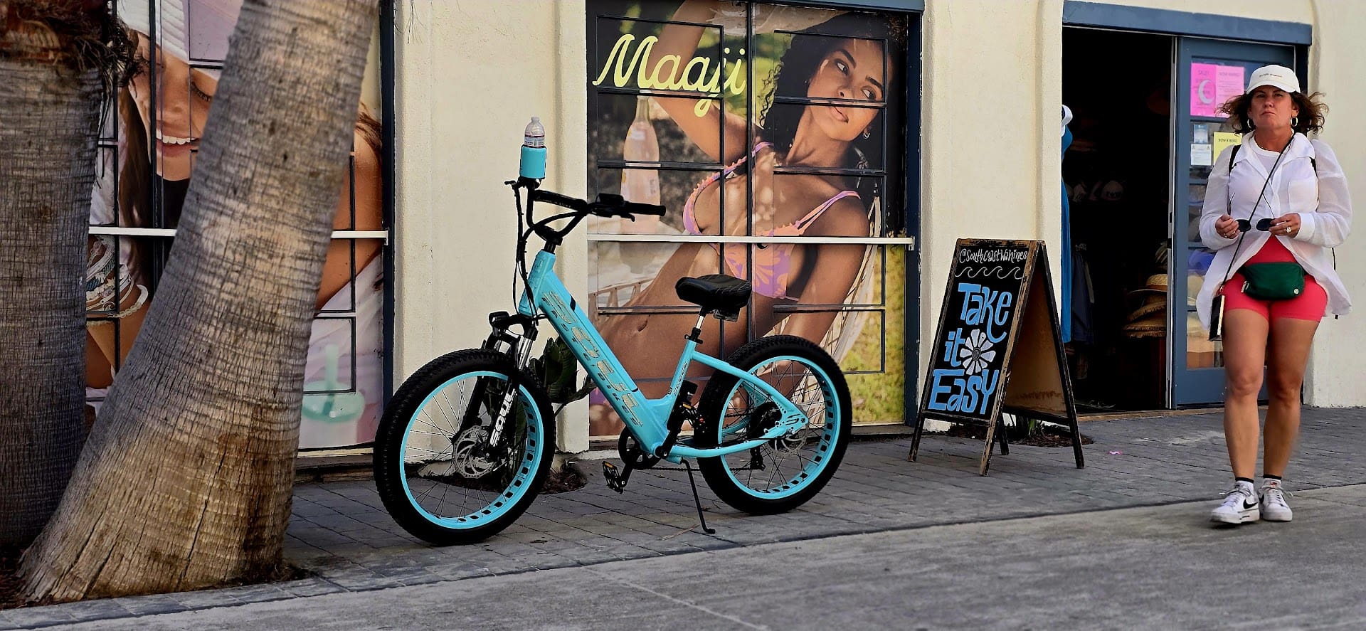 Blue bicycle parked outside a clothing store.