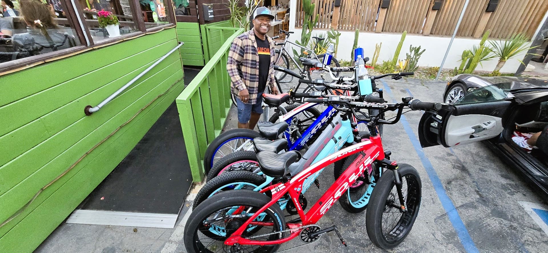 Man with bicycles outside a green building.