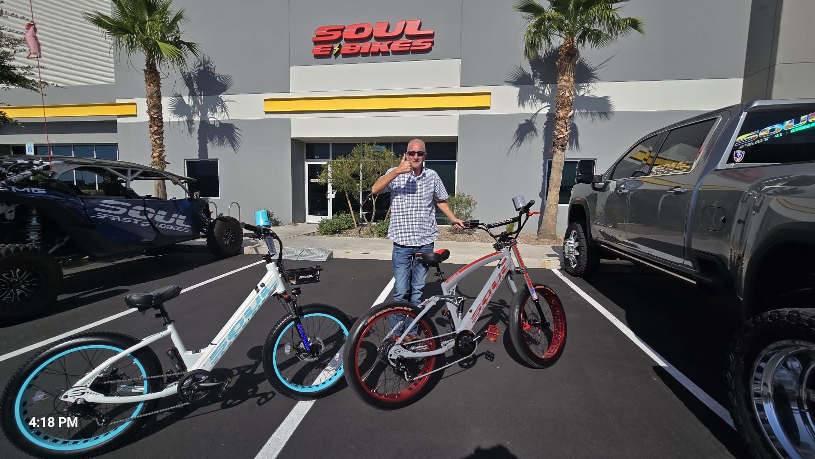 Man standing between two bicycles outside store.