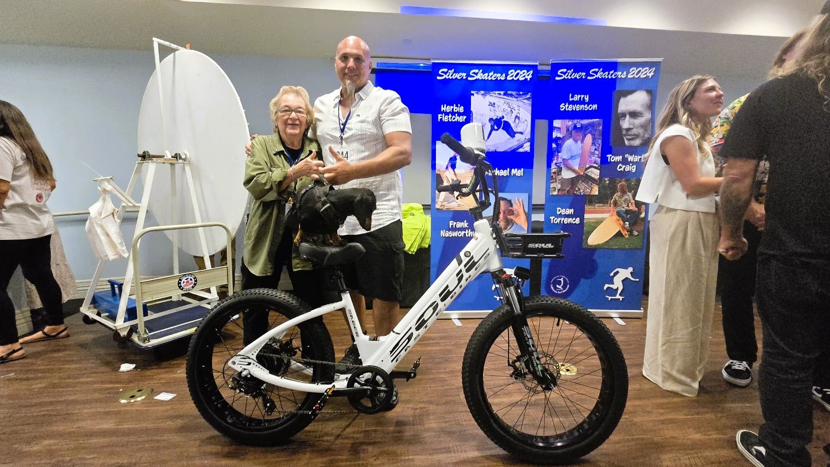 Two people posing with an electric bicycle.