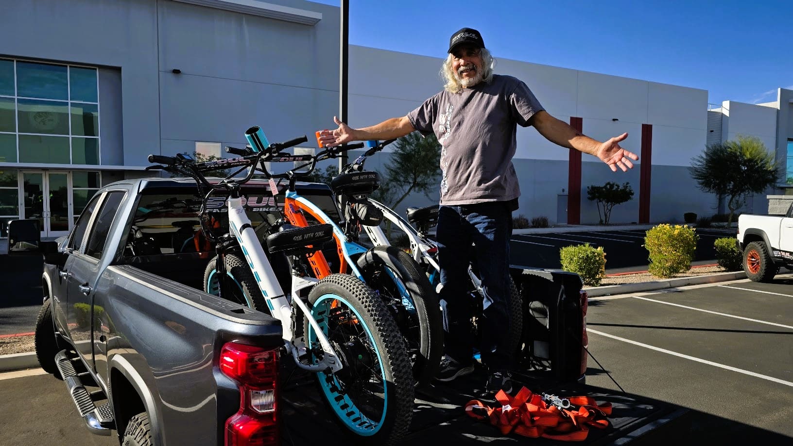 Man with electric bikes on truck bed.