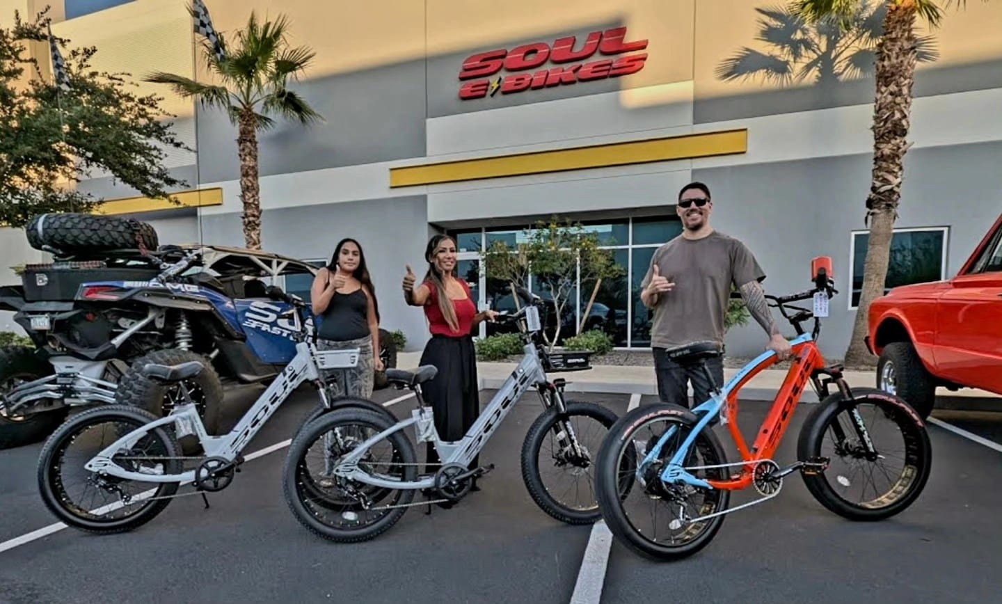 Three people with bikes outside Soul eBikes.