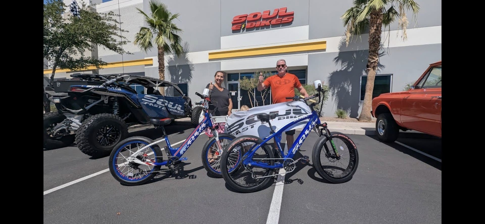 Two people with electric bikes outside store.
