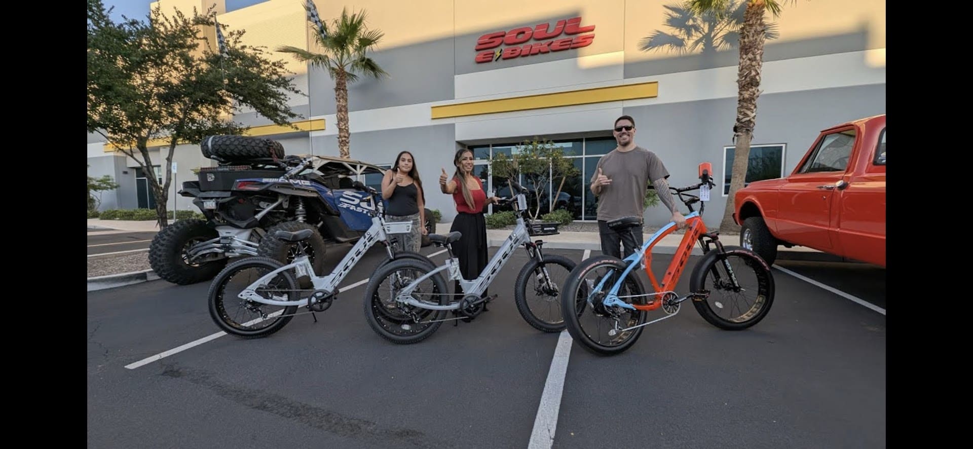 People with electric bikes in parking lot.