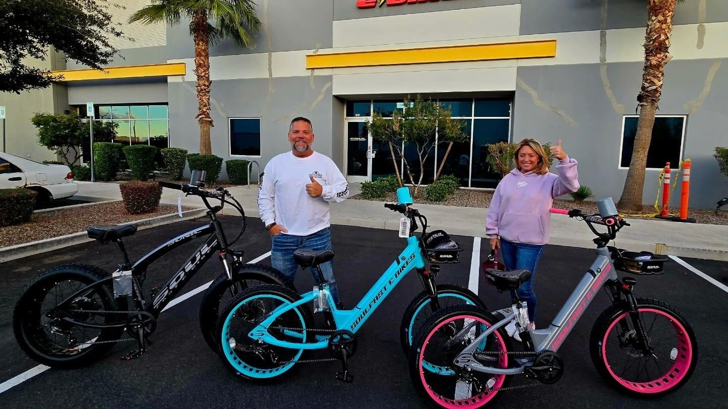 Two people with electric bikes outside building.
