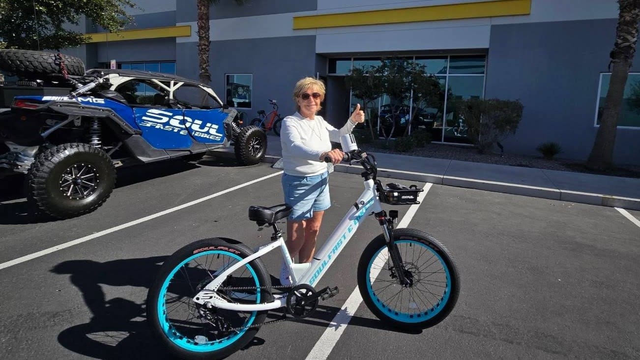 Woman giving thumbs up beside electric bike.