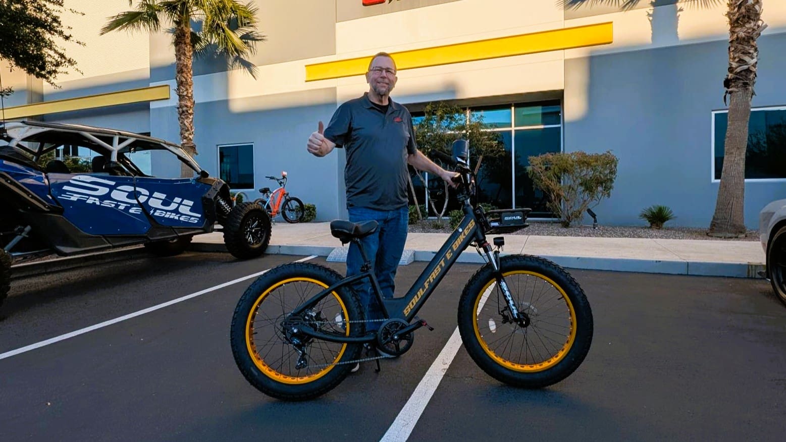 Man with thumbs up beside electric bike.