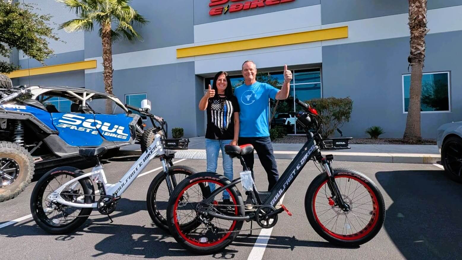 Two people with electric bikes, thumbs up.