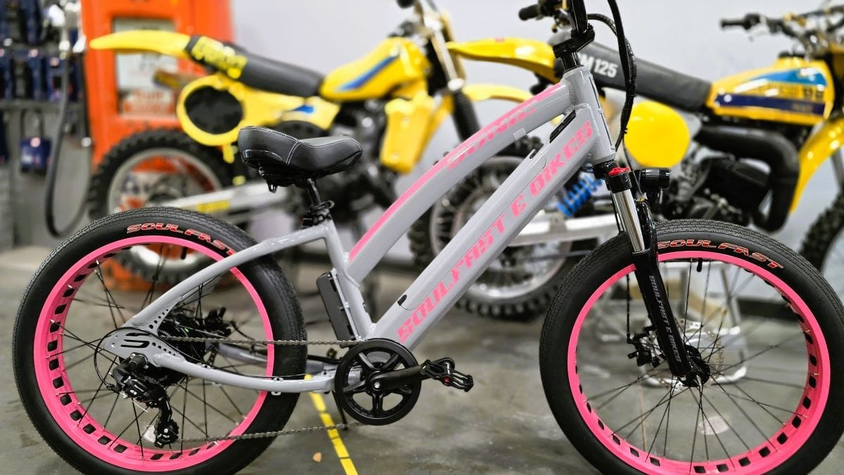 Gray bicycle with pink rims in shop.